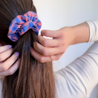 Chouchou artisanal Violette à carreaux vichy bleu et rose porté en demi-queue de cheval sur de longs cheveux bruns.