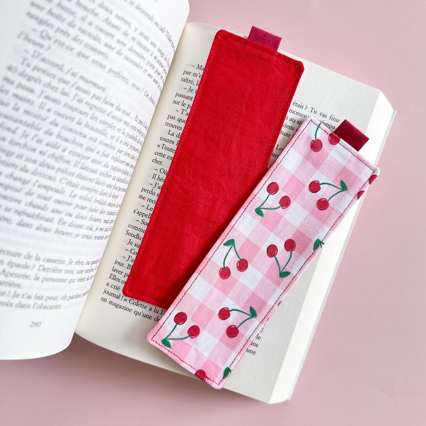Rescto et verso du marque-page en tissu, montrant la face vichy rose et cerises et le dos en tissu coton uni rouge vif.