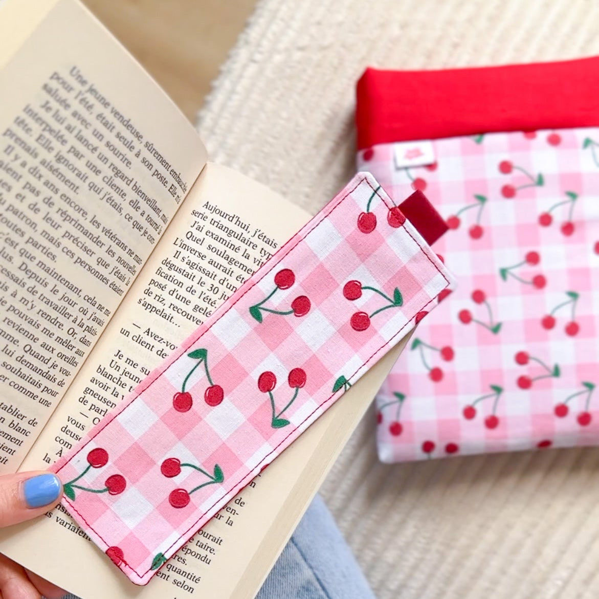 Marque page en tissu vichy rose cerise tenu en main assorti à sa pochette à livre. Cadeau idéal et original pour lectrice.