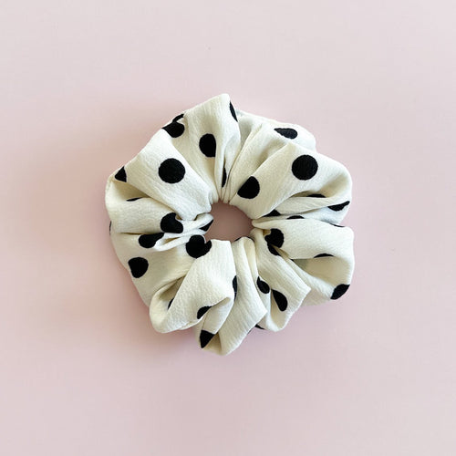 Gros chouchou cheveux Daphné blanc à pois noirs, accessoire femme de fabrication artisanale présenté à plat.