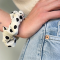 Chouchou Daphné blanc à pois noirs porté au poignet comme un bracelet, création de fabrication artisanale.