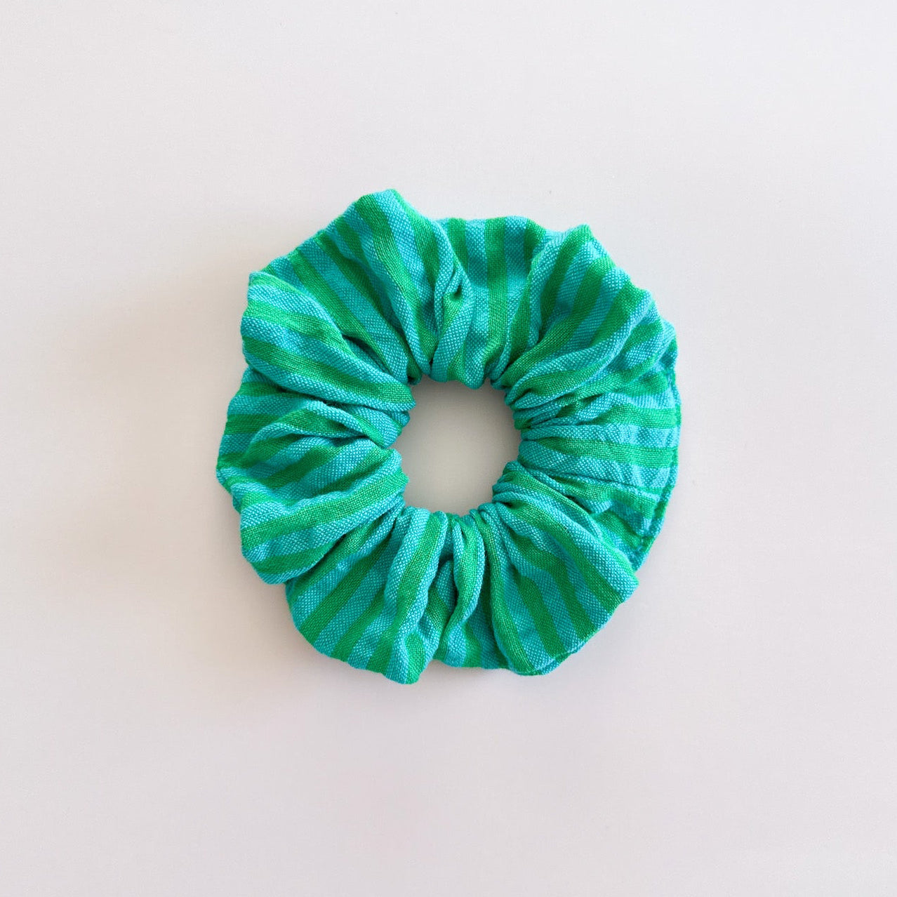 Chouchou cheveux Siena en gaze de coton à rayures vertes et bleu turquoise, de fabrication artisanale, présenté à plat.