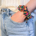 Chouchou Daisy à petites marguerites porté en bracelet au poignet, création de fabrication artisanale en jersey hyper confortable.