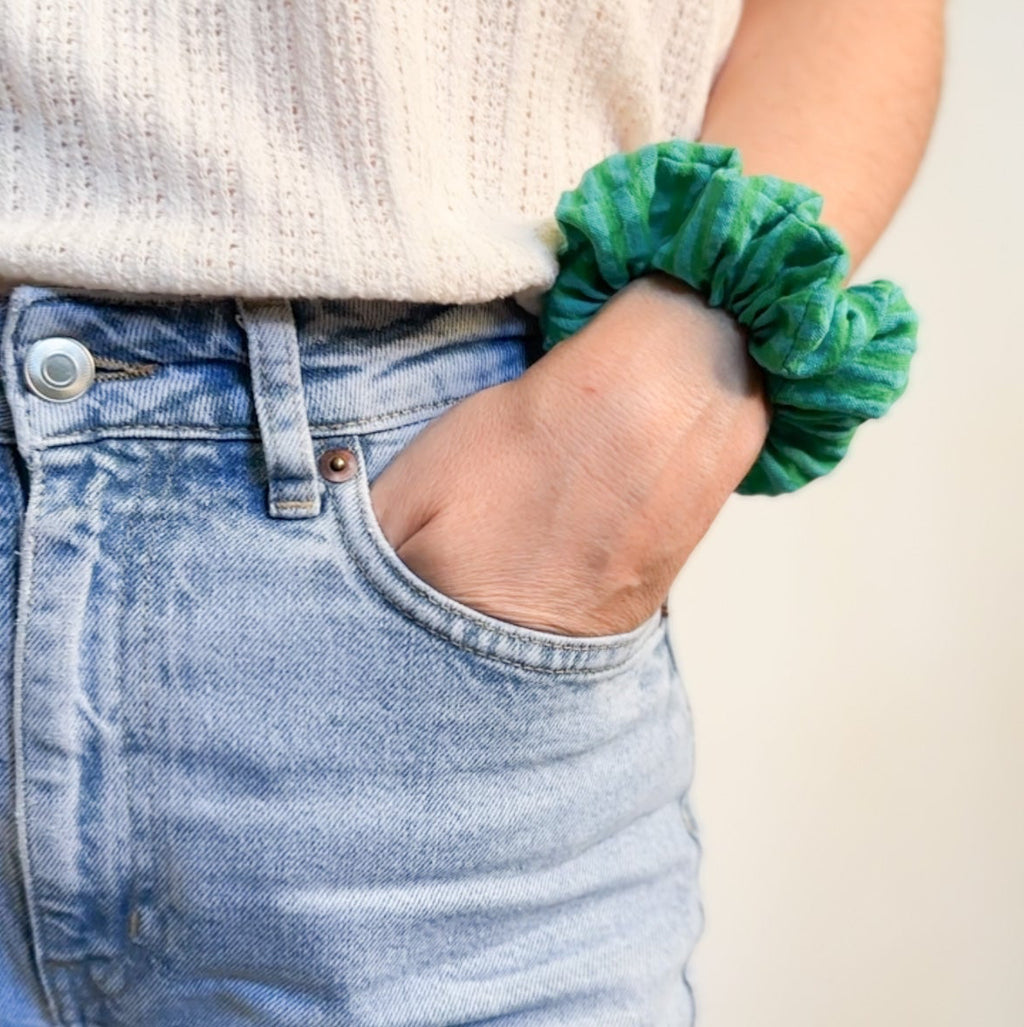 Chouchou Siena en gaze de coton à rayures vertes et turquoise porté en bracelet avec un jean, une création de fabrication artisanale.