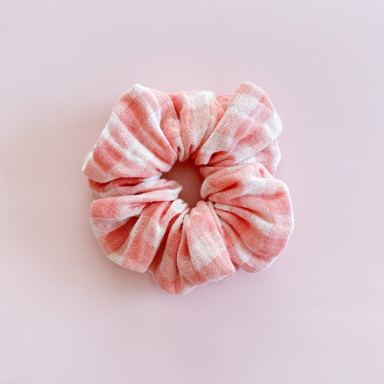 Gros chouchou cheveux Chiara en gaze de coton vichy rose pastel et blanc de fabrication artisanale, accessoire femme doux et romantique de la marque Jolie Myrtille présenté à plat.
