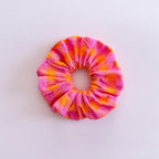 Gros chouchou cheveux vichy rose et orange Suzie de fabrication artisanale, accessoire femme coloré de la marque Jolie Myrtille présenté à plat.