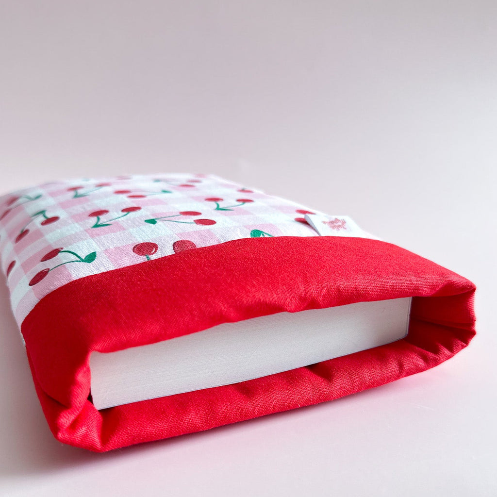 Gros plan sur l'ouverture d'un protège livre montrant sa doublure en coton rouge et son rembourrage molletonné pour protéger les romans des chocs.
