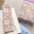 Marque page en tissu fleuri pastel et vintage cousu main posé sur un livre ouvert, accompagné de sa pochette à livre assortie.