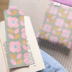 Marque page en tissu fleuri pastel et vintage cousu main posé sur un livre ouvert, accompagné de sa pochette à livre assortie.