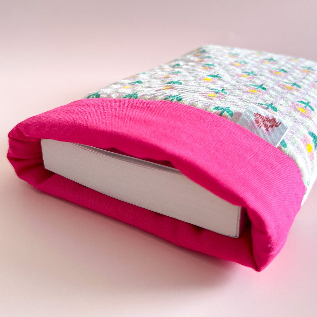 Détail de l'ouverture d'une pochette à livre en tissu rose montrant l'épaisseur du rembourrage avec un livre à l'intérieur pour une protection optimale.