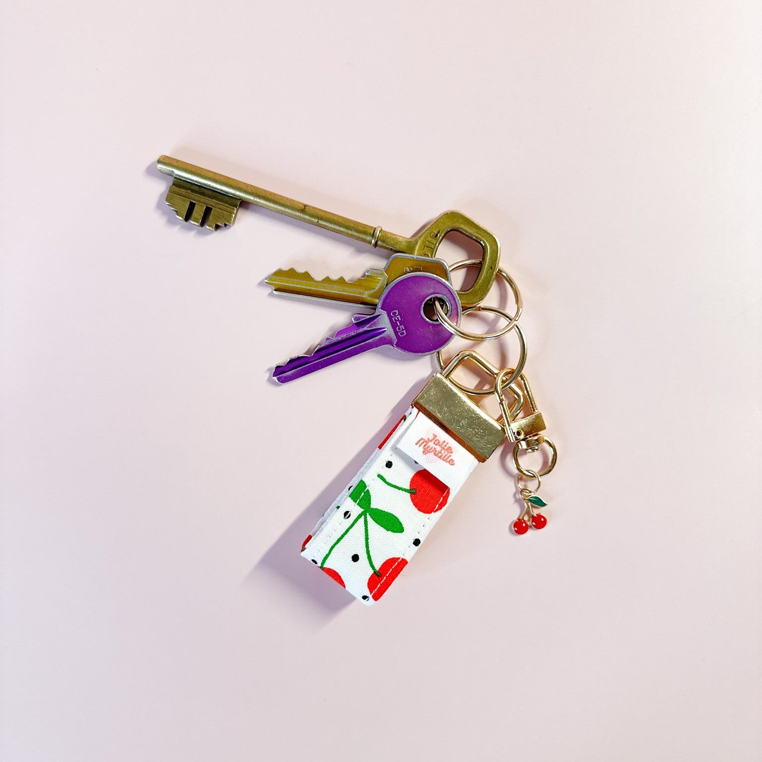 Porte-clés en tissu motif cerises accroché à un trousseau de clés, utilisé comme un grigri coloré et pratique au quotidien.
