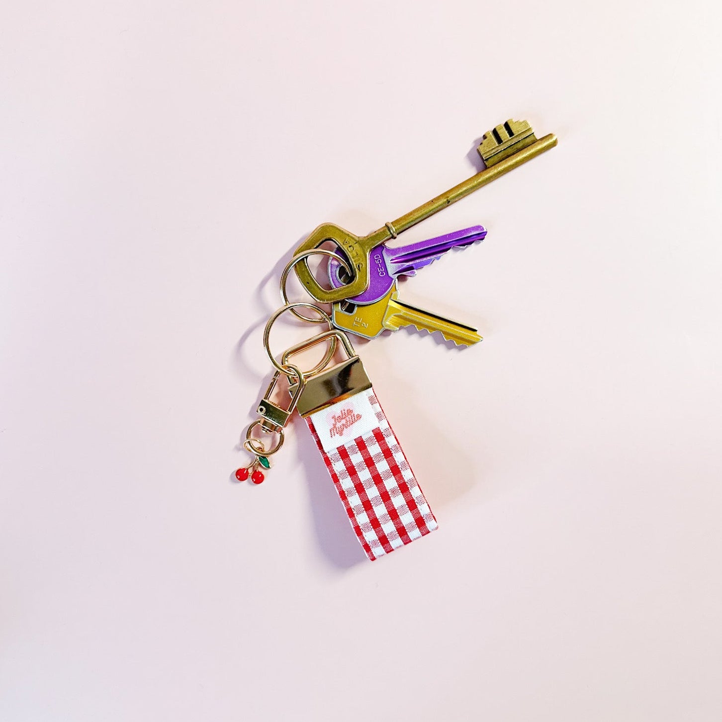 Porte-clés Anna en tissu vichy rouge accroché à un trousseau de clés, utilisé comme un grigri de sac coloré et pratique au quotidien.