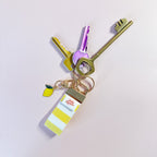 Porte-clés Limoncello en tissu rayé jaune accroché à un trousseau de clés, utilisé comme un grigri de sac estival et pratique au quotidien.
