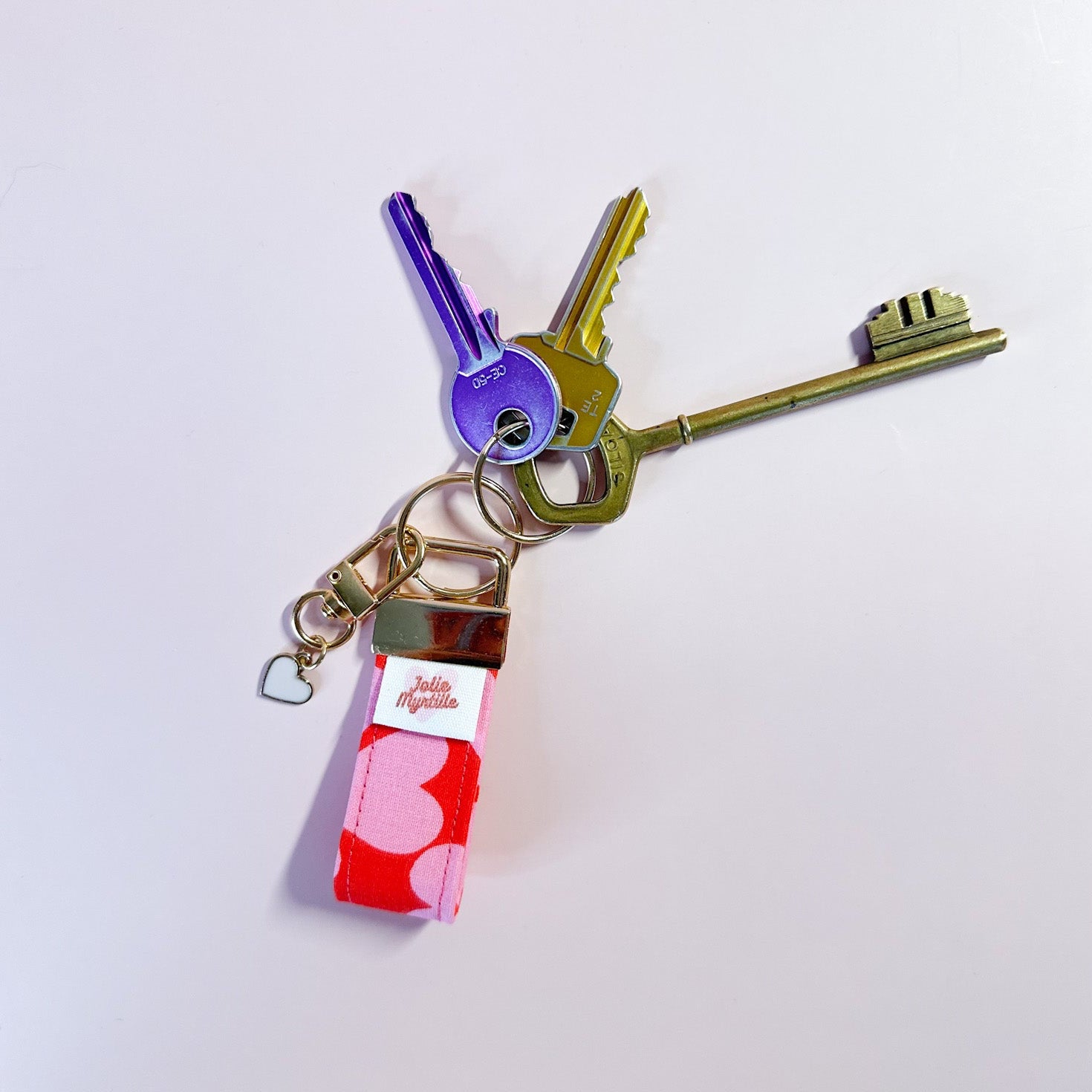 Porte-clés Scarlette en tissu rouge et rose accroché à un trousseau de clés, utilisé comme un grigri de sac coloré et pratique.
